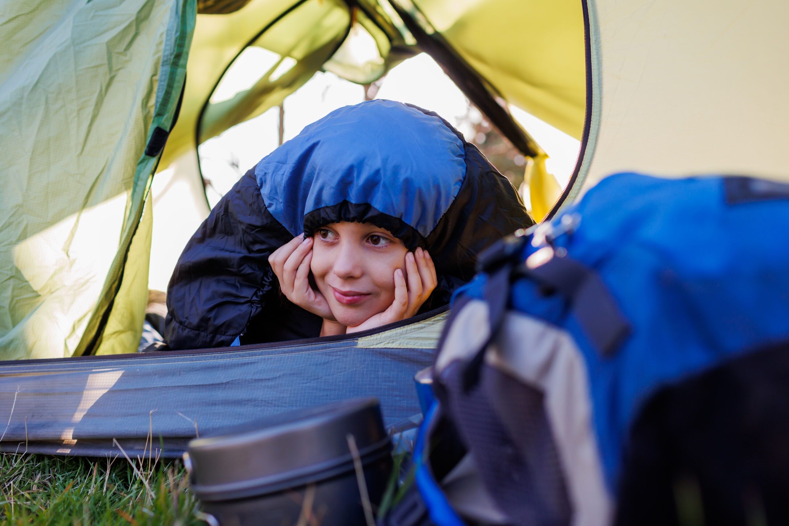 Smiling camper cozy in a sleeping bag inside a tent